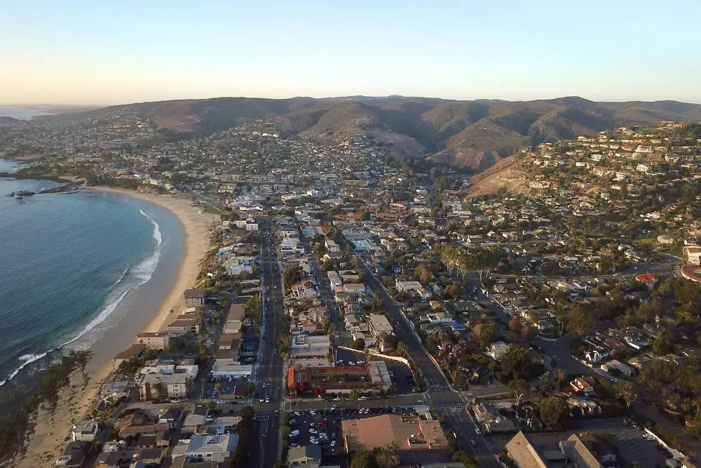 Aerial view of a coastal town and beach below hills